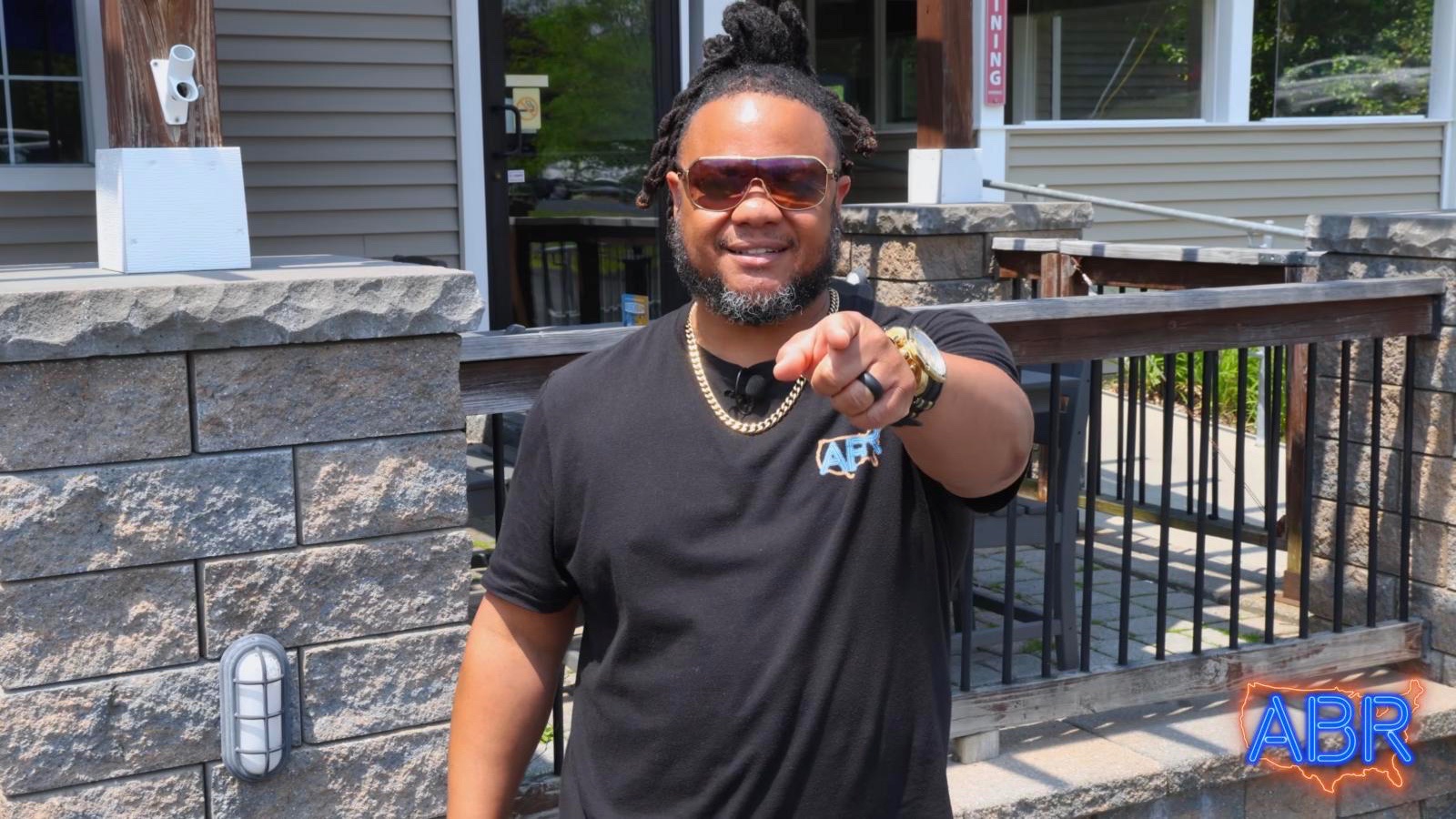 America's Best Restaurants host Theo Williams pointing to the camera outside Cooper Hill