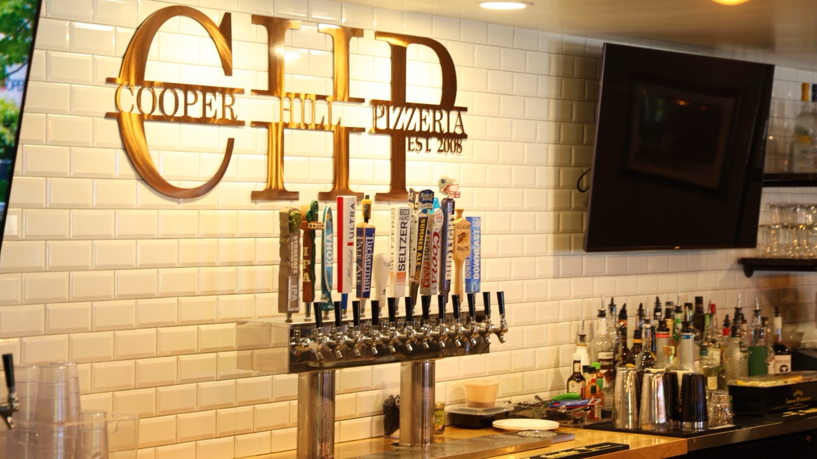 The draft taps and back bar under the Cooper Hill Pizzeria logo